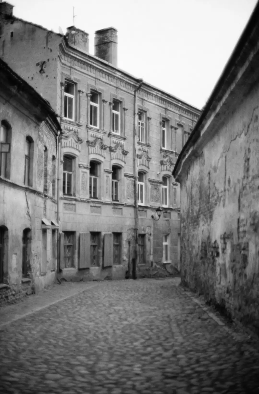 An old style grayscale photo of a city alley. Created and photographed by Hiroku