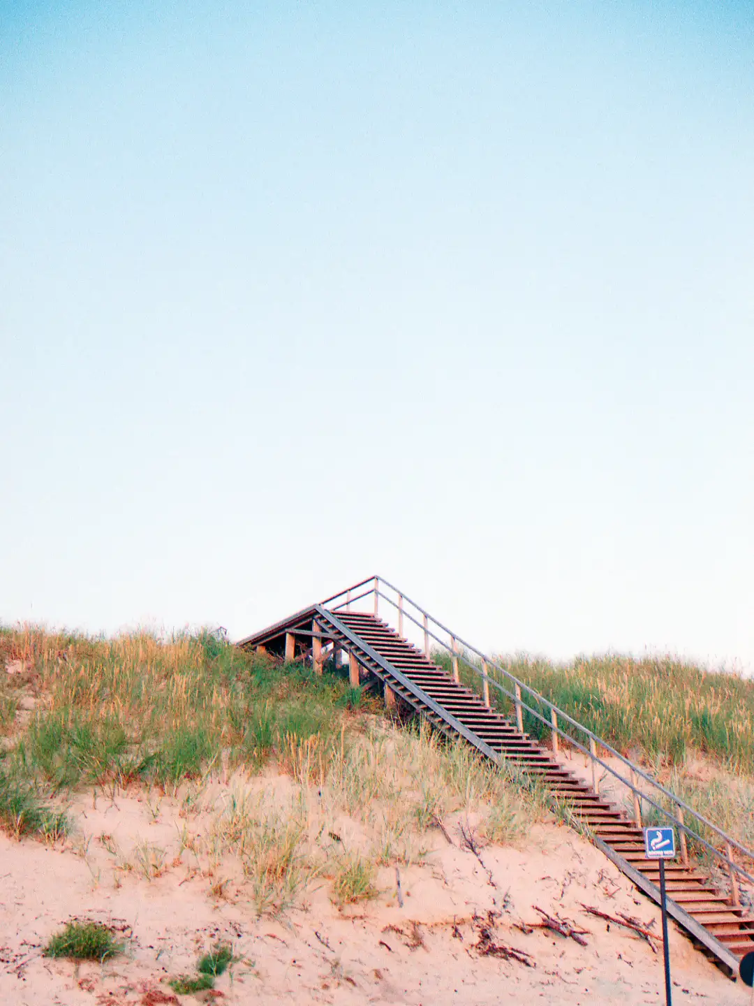 An image of a wooden staircase leading to the top of a sand dune. Created and photographed by Hiroku