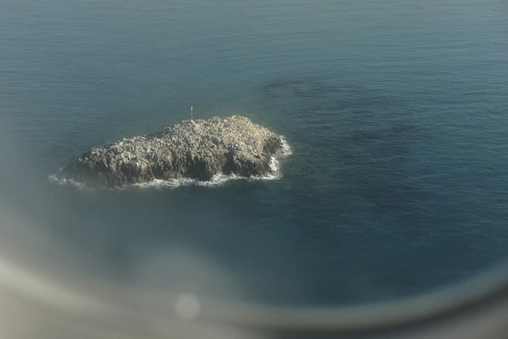 A picture of a small rock island taken from an airplane. Created and photographed by Hiroku